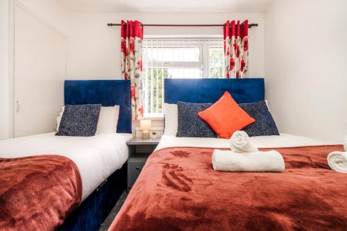 deux lits dans une chambre avec du rouge et du bleu dans l'établissement Laurel Luxury Business, Families, Harrry Porter, Industrial Area, à Hemel Hempstead