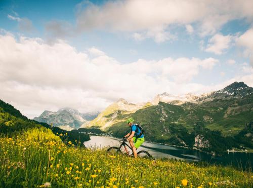 a man riding a bike on a hill overlooking a valley at Schweizerhaus Swiss Quality Hotel in Maloja
