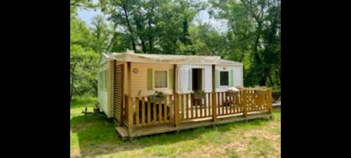a small yellow caravan with a porch in a yard at Mobil-home du lot Dordogne in Milhac