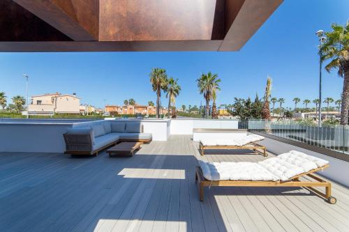 a roof deck with two beds and a couch at Oceans Oliva in Oliva