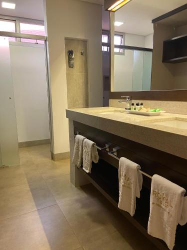 a bathroom with a sink and a mirror and towels at Hotel JP Ribeirão Preto Resort & Convenções by Nacional Inn in Ribeirão Preto