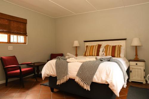 una camera da letto con un letto grande e una sedia rossa di Concordia Kloof Cottage a Baardskeerdersbos