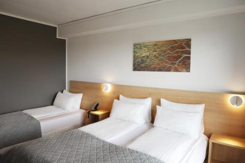 two beds in a small room with white pillows at Fosshotel Nupar in Kálfafell