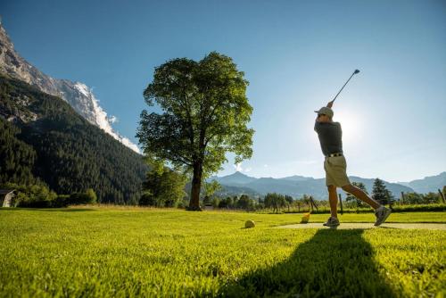 a man is playing golf in a field at Derby Swiss Quality Hotel in Grindelwald