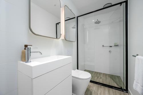 a white bathroom with a sink and a toilet at Luxe 3BR Skyline Sunset Residence Level 63 - CBD Views, Parking, Pool, Sauna, Gym in Melbourne