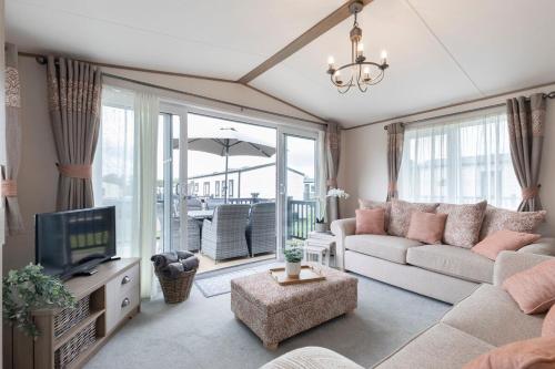 a living room with a couch and a tv at Peaceful Millers Lodge at The Cotswold Water Park in South Cerney