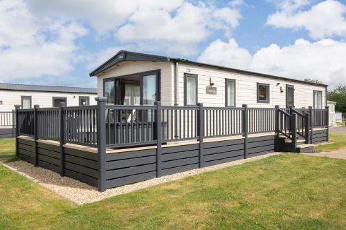 a small house with a black fence at Peaceful Millers Lodge at The Cotswold Water Park in South Cerney
