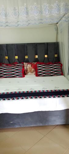 a bed with red and black pillows on it at Hotel Judith, GULU in Buwate