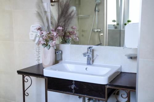 a bathroom with a sink and a mirror and flowers at Boutique Hotel Aviator in Belgrade