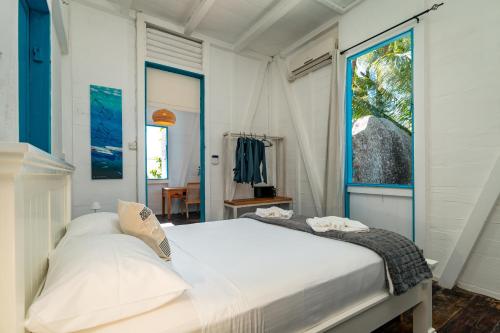 a bedroom with a large white bed and a window at Beach House Beau Vallon in Beau Vallon