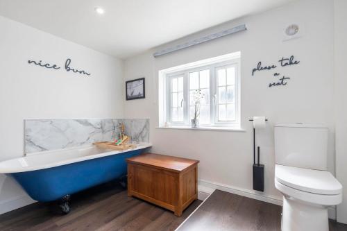 a bathroom with a blue tub and a toilet at Beautiful Danford House & Lodge with Hot Tub in Hartpury