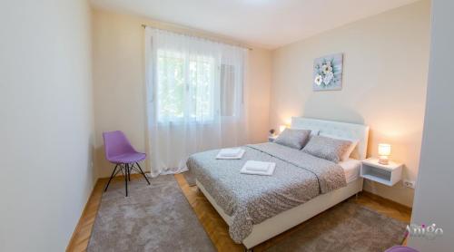 a bedroom with a bed and a purple chair at Holiday Home Leo in Mostar