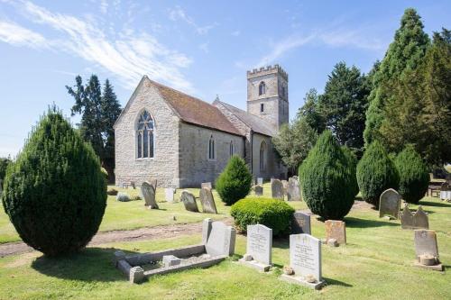 an old church with a bunch of graves in front at Beautiful Danford House & Lodge with Hot Tub in Hartpury