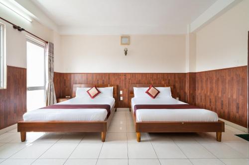 a room with two beds in a room with a window at Collection O Nam Phuong Hoang Hau Near Lotte Mart in Ho Chi Minh City