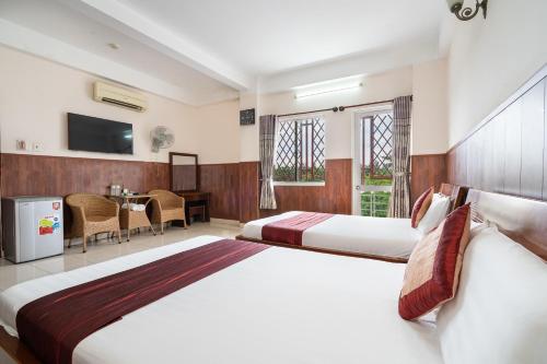 a hotel room with two beds and a television at Collection O Nam Phuong Hoang Hau Near Lotte Mart in Ho Chi Minh City
