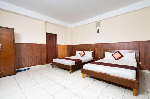 a hotel room with two beds and a cabinet at Collection O Nam Phuong Hoang Hau Near Lotte Mart in Ho Chi Minh City