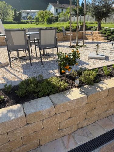 a retaining wall with two chairs and a table and some flowers at Hotel Restaurant Croix Blanche in Sugiez