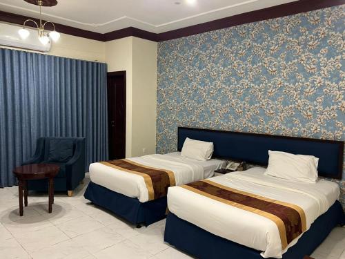 a hotel room with two beds and a chair at Twilight Hotel in Muscat