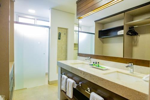 a bathroom with a sink and a large mirror at Hotel JP Ribeirão Preto Resort & Convenções by Nacional Inn in Ribeirão Preto