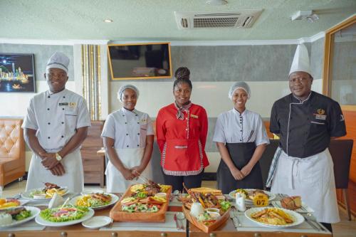 a group of people standing in front of a table of food at Tiffany Diamond Hotels LTD - Makunganya in Dar es Salaam