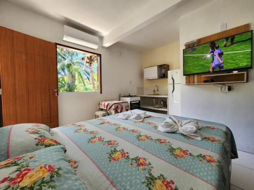 a bedroom with a bed with a television on the wall at Residencial dos Ipês in Itacaré