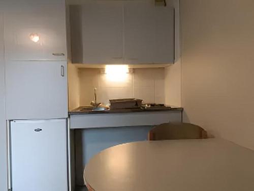 a kitchen with a table and a white refrigerator at VVF Plaine d'Alsace Obernai Strasbourg in Obernai