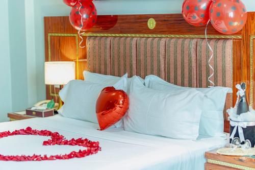 a bed with a red pillow and balloons on it at Tiffany Diamond Hotels LTD - Makunganya in Dar es Salaam