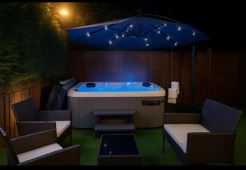 a hot tub with an umbrella and chairs and a table at Stylish & Brand-New Home 2025 in Moortown