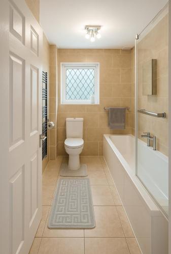 a bathroom with a toilet and a tub and a window at Stylish & Brand-New Home 2025 in Moortown