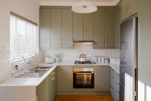 a kitchen with green cabinets and a sink and a stove at Goedehoop Boutique Apartment in Robertson