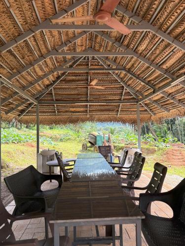 a table and chairs under a wooden roof at Lead Farm Stay in Palakkad