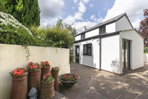 a white house with flower pots in front of it at Tranquil Cottage with Hot Tub in Skenfrith