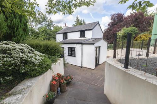a white house with a fence and some plants at Tranquil Cottage with Hot Tub in Skenfrith