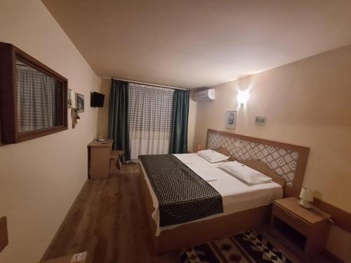 a bedroom with a bed and a large window at Norica Guesthouse in Gura Rîului