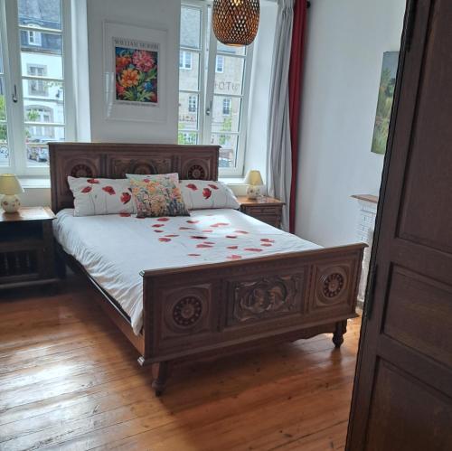 a bedroom with a large wooden bed with flowers on it at Bel appartement au centre in Huelgoat