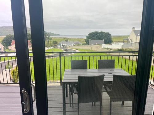 a table and chairs on a balcony with a view at Ocean Breeze in Dunfanaghy
