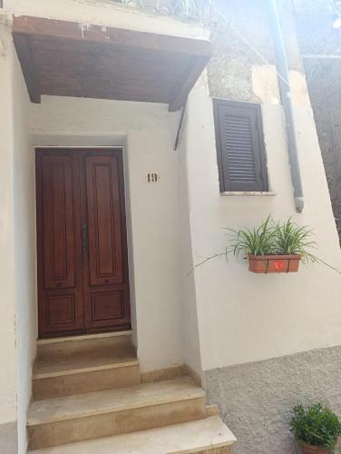 ein Haus mit Holztür und einigen Pflanzen in der Unterkunft Alloggio Turistico La Rupe in Norma