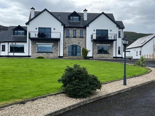a large house with a green lawn in front of it at Ocean Breeze in Dunfanaghy