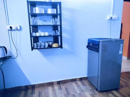 a blue wall with a shelf and a refrigerator at Shalom Deluxe Luxury Apartments and Villa in Colva