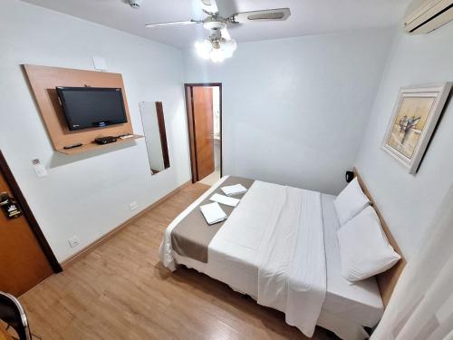 a bedroom with a white bed and a flat screen tv at Hotel Itapema in Valinhos