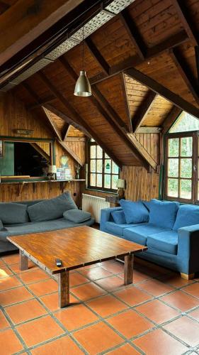 a living room with blue couches and a wooden table at Alaska Patagonia Hostel in San Carlos de Bariloche