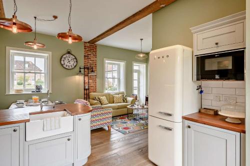 a kitchen with a white refrigerator and a living room at Thymblethorpe - Blythview in Blyford