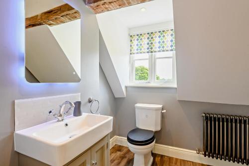 a bathroom with a sink and a toilet and a window at Thymblethorpe - Blythview in Blyford