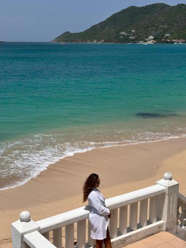 a woman standing on a fence near the beach at Grand Case Beachfront Apartment in Grand Case