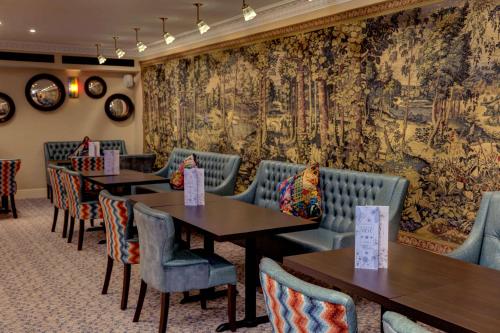a dining room with tables and chairs and a wall mural at Sure Studio Doncaster in Doncaster