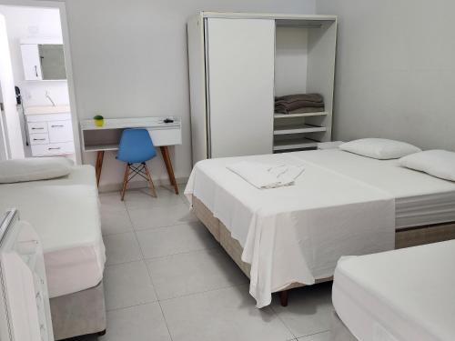 a bedroom with two beds and a desk and a blue chair at FRANCIS HOTEL MAR in Caraguatatuba