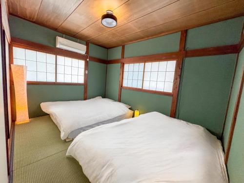 two beds in a room with two windows at Totono Amami in Karitachō