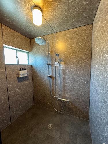 a bathroom with a shower with a glass door at Totono Amami in Karitachō