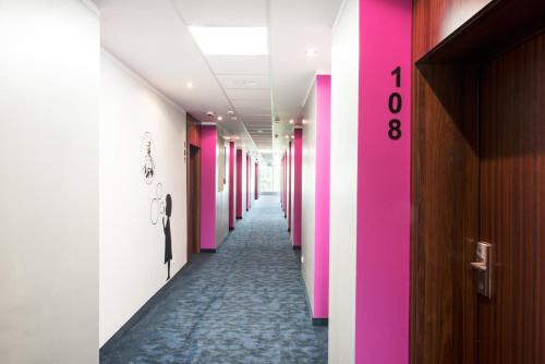 a corridor of a hallway with pink and white walls at Ibis Styles Gniezno Stare Miasto in Gniezno