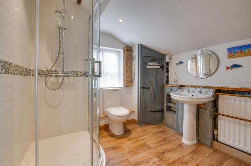 een badkamer met douche, wastafel en toilet bij Dressmakers Cottage in Wrentham